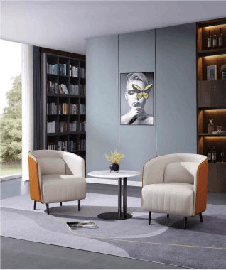 Modern lounge with two beige armchairs and a round table holding a small plant. Bookshelves line the wall, and a butterfly artwork adds elegance. Cozy ambiance.