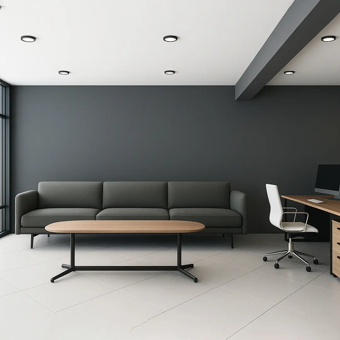 Modern office space with a dark gray sofa, oval wooden coffee table, and white office chair by a wooden desk. Minimalist and sleek atmosphere.