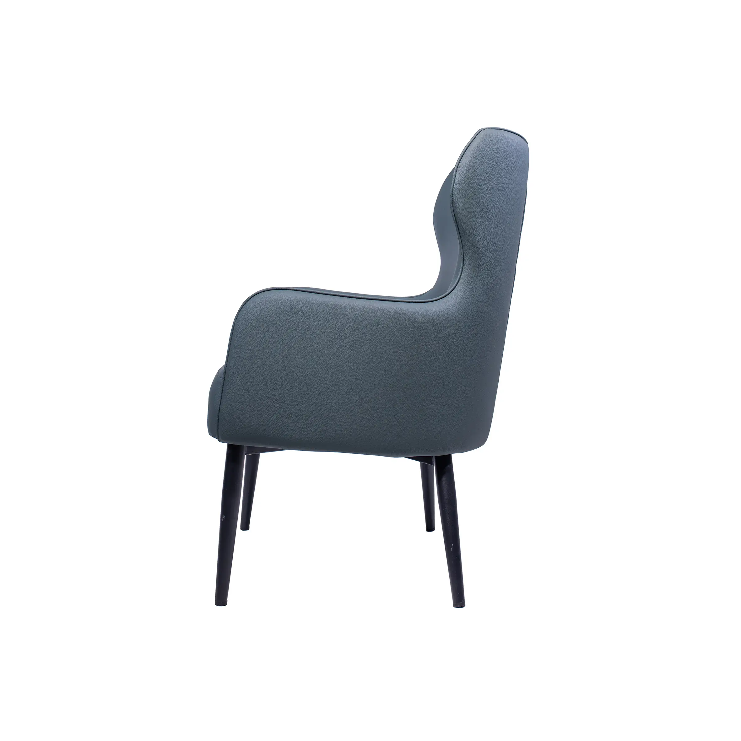 Modern office space with two dark gray armchairs facing a round black table. Background features white desks and office chairs near large windows.