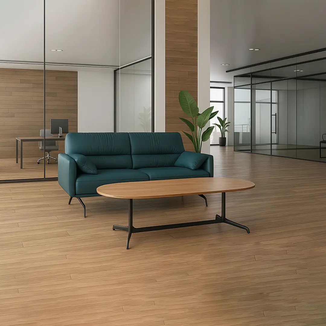 Modern office lounge with a teal sofa, wooden coffee table, and large potted plant against glass walls. The space feels sleek and inviting.