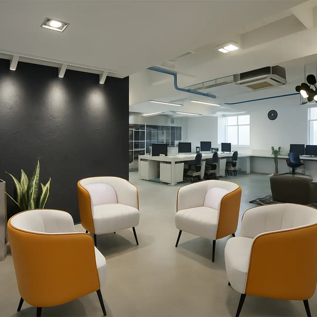 Modern office space with a cozy lounge area featuring four orange and white chairs. In the background are desks with computers, creating a professional yet inviting ambiance.