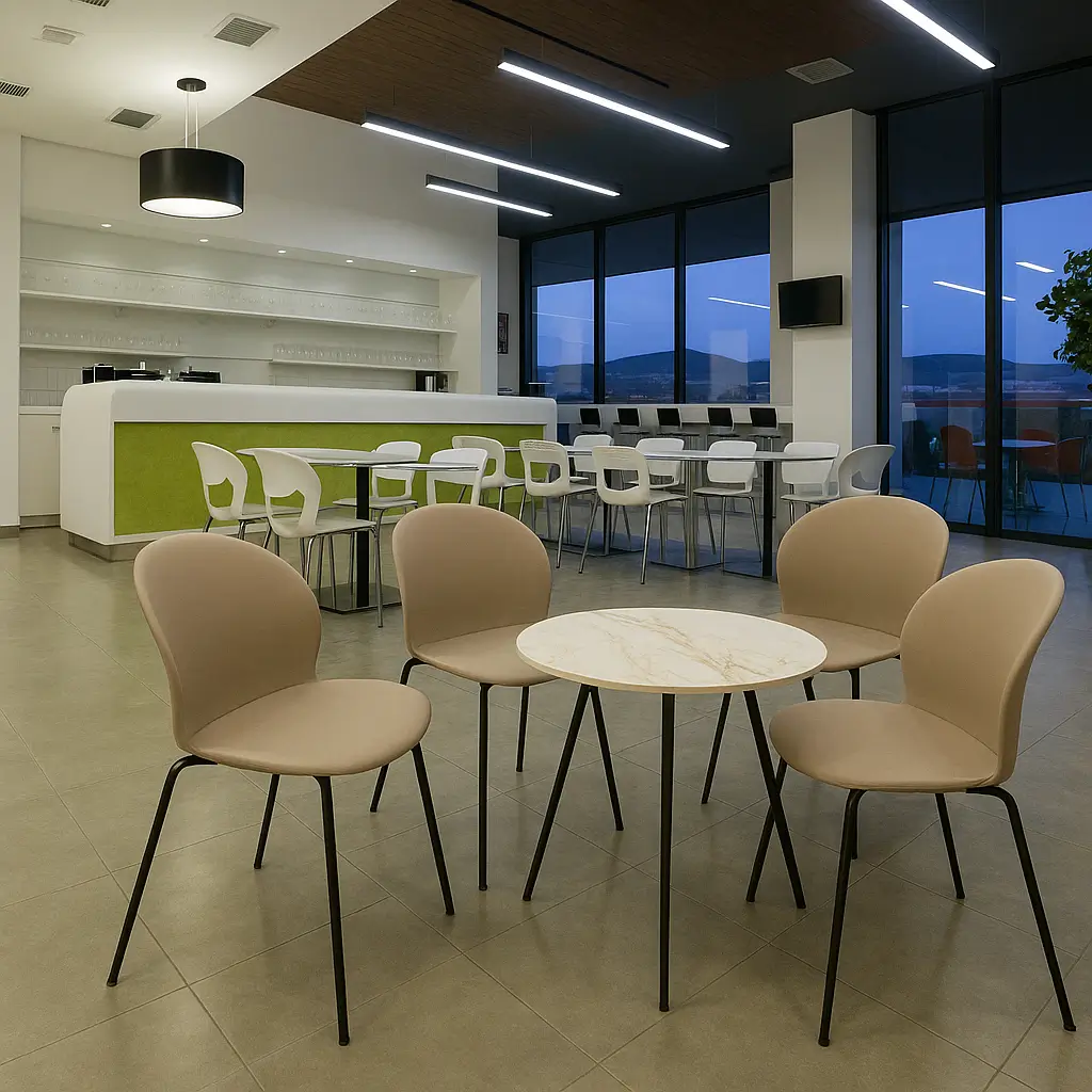 Modern cafe interior featuring a round marble table with four beige chairs in the foreground. Bar counter with green accents and large windows in the background.