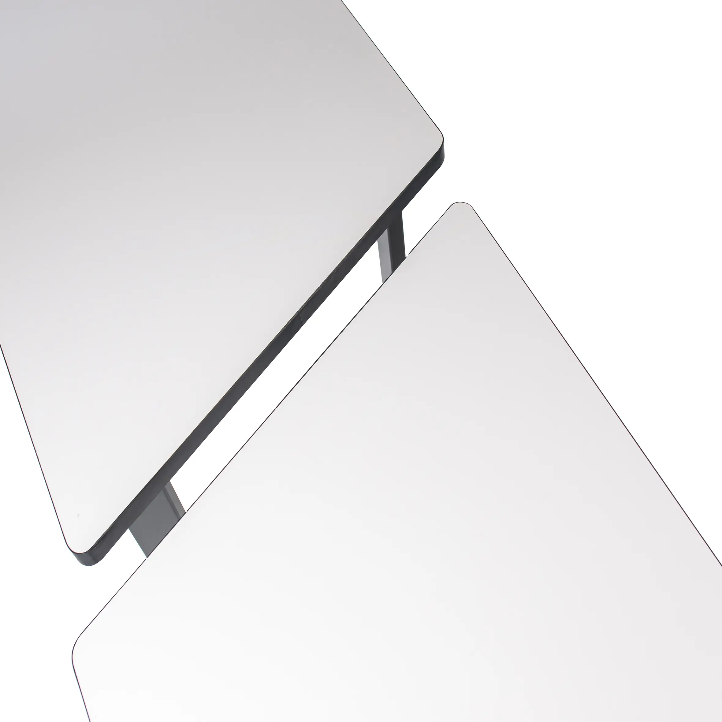 Modern office setting with a trapezoidal white desk and a black mesh swivel chair on wheels. Neutral tones and a bright window create a minimalist, professional vibe.