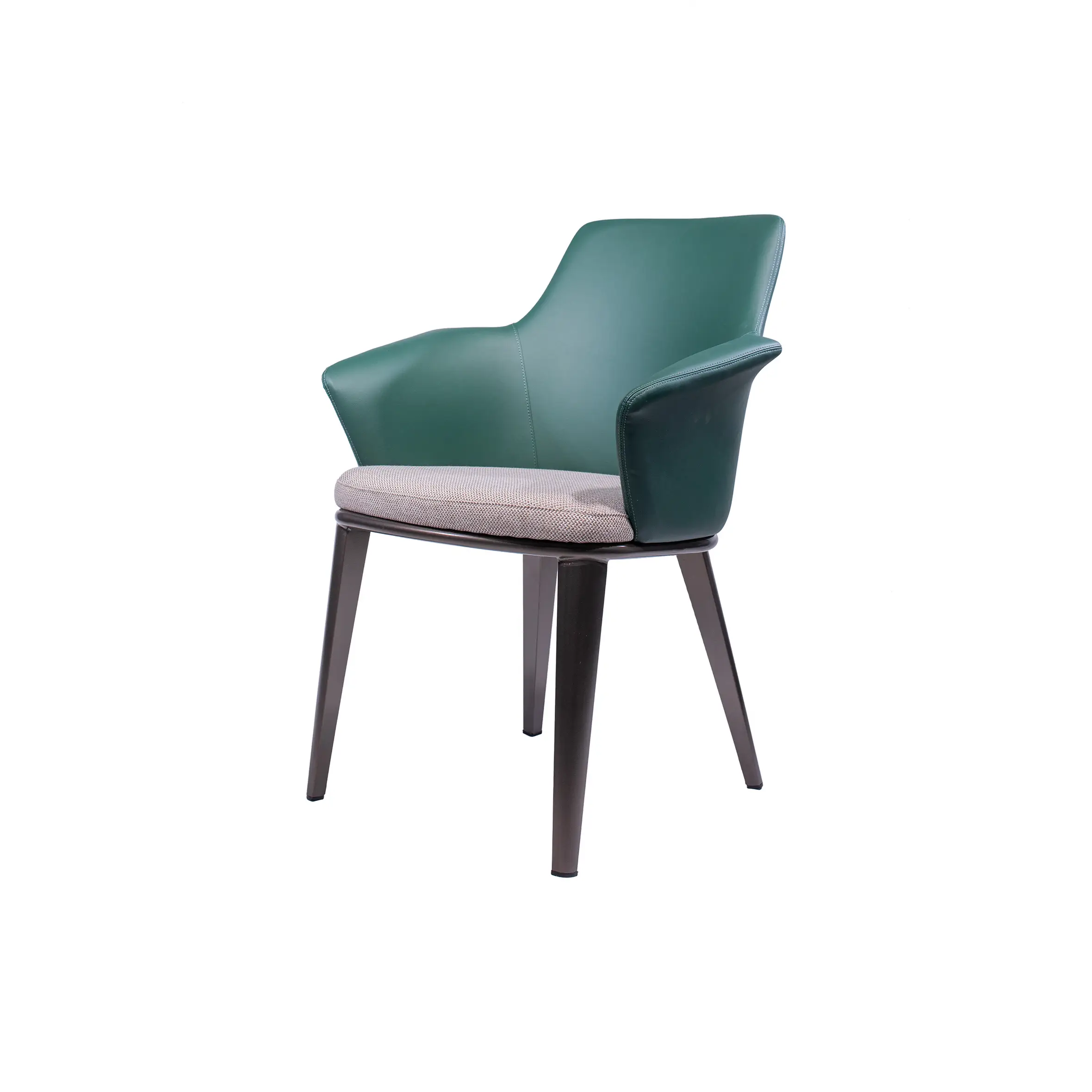 Green armchair with a gray cushion beside a wooden side table on a carpeted floor. Background shows a modern lounge with large windows and a sofa.