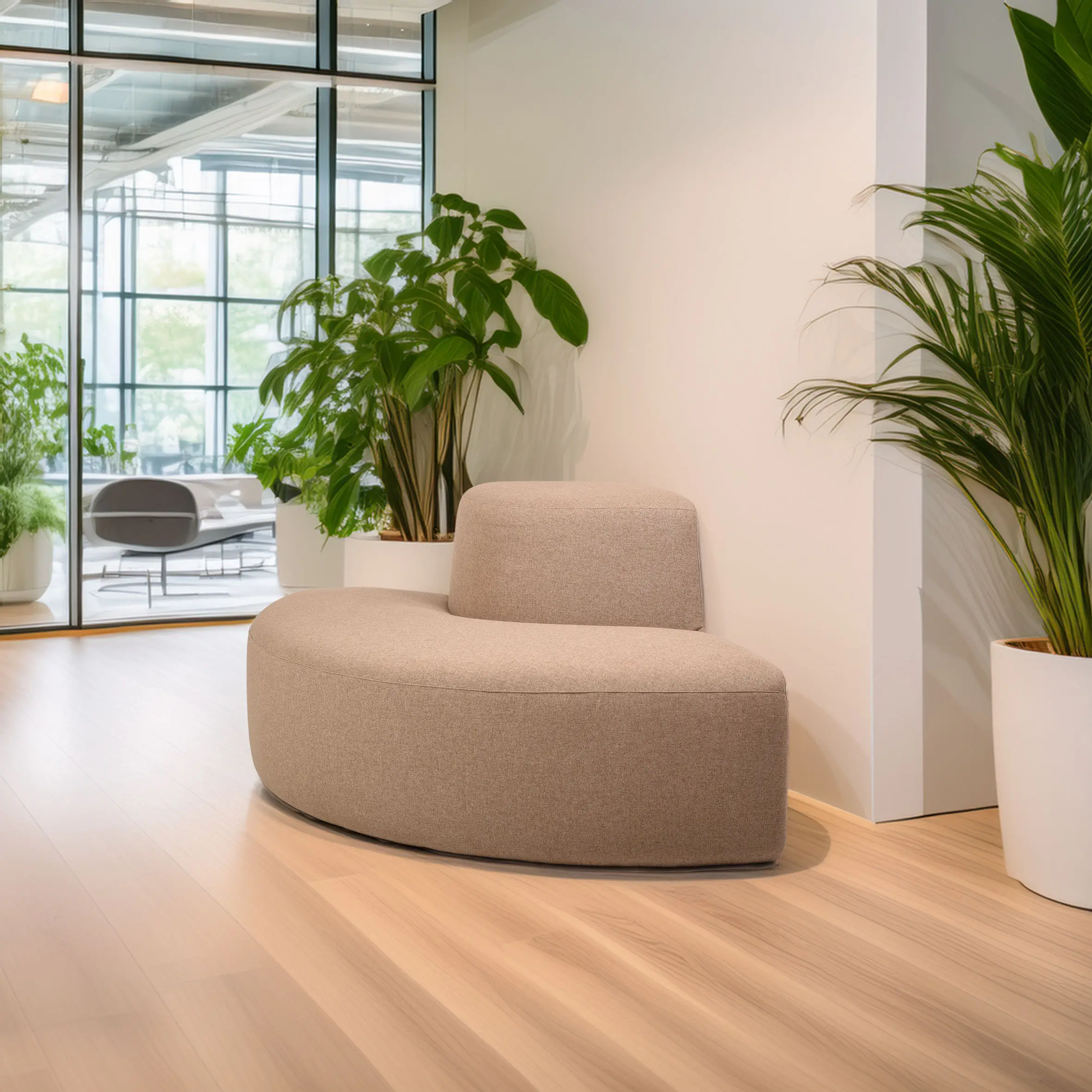 Modern lobby area with a beige curved sofa, wooden floor, and large potted plants. Floor-to-ceiling windows reveal a bright green outdoor view.
