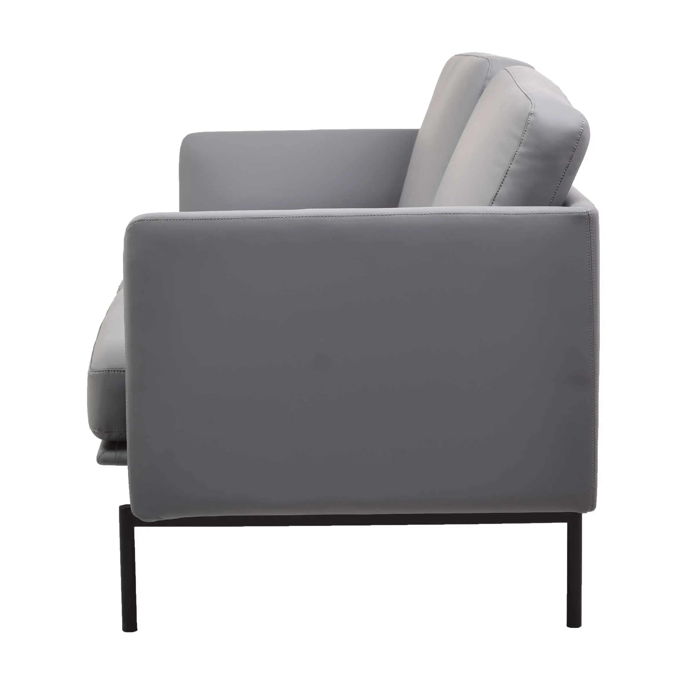 Modern office lounge with a grey sofa and ottoman on a textured rug. Large windows offer a city view, and potted plants add a fresh touch.