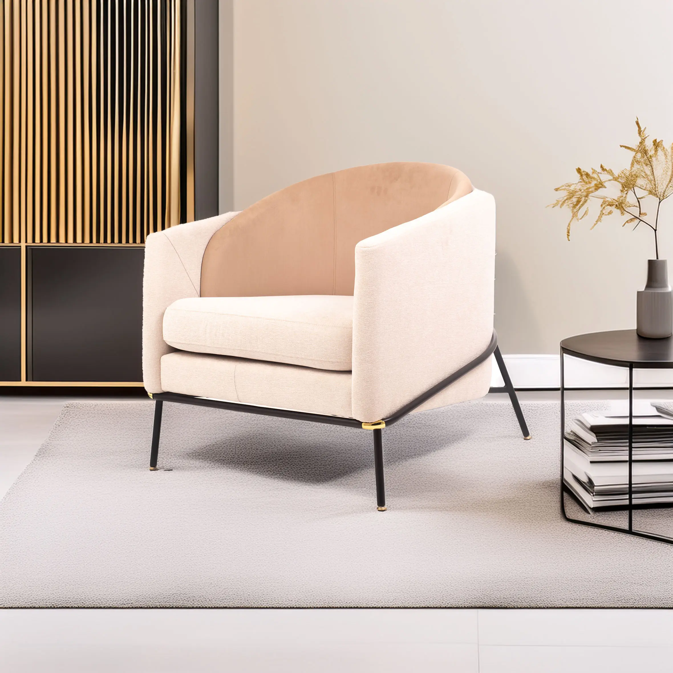 A modern beige armchair with black legs rests on a light gray rug. A round table with stacked magazines and a vase with dried flowers is beside it.
