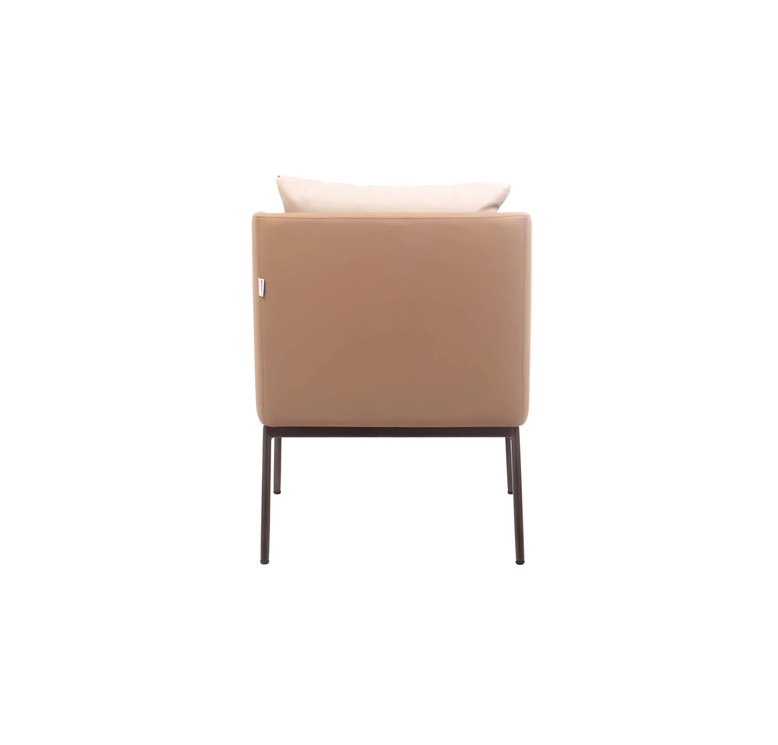 Modern living room with a light beige armchair and white cushion on a large cream rug. A glass coffee table holds two books. Large plants add greenery.