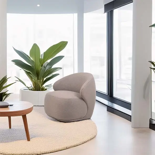 A cozy, modern room with a gray curved armchair on a round beige rug. Tall green plants in white pots and large windows create a bright, serene atmosphere.