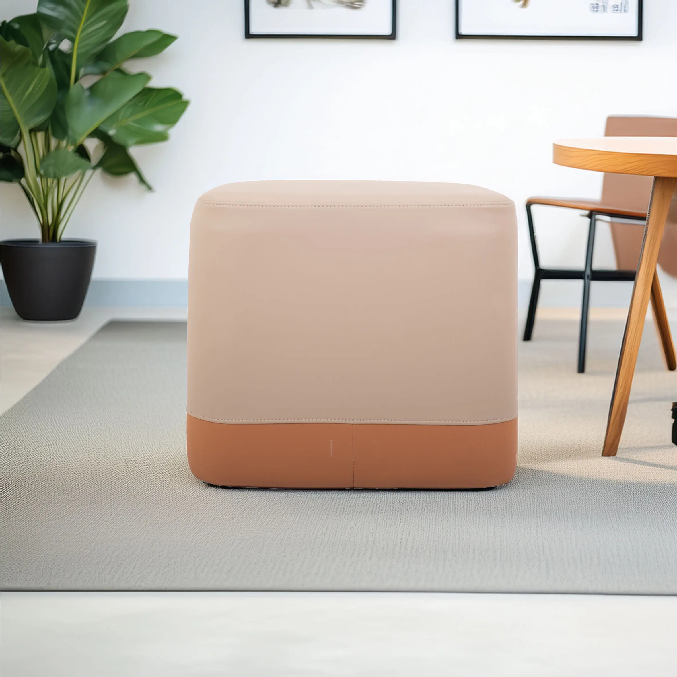 A modern, beige and orange ottoman sits on a textured gray carpet. Nearby are a wooden table and a potted plant, creating a cozy, minimalist setting.