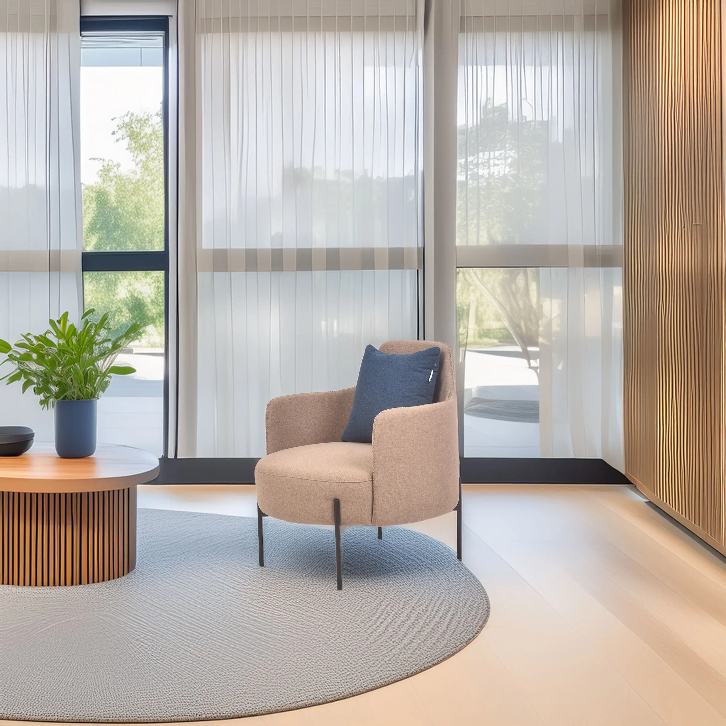 A cozy room with a beige armchair and blue pillow on a circular gray rug. A round wooden table with a plant is nearby, against light-filled sheer curtains.