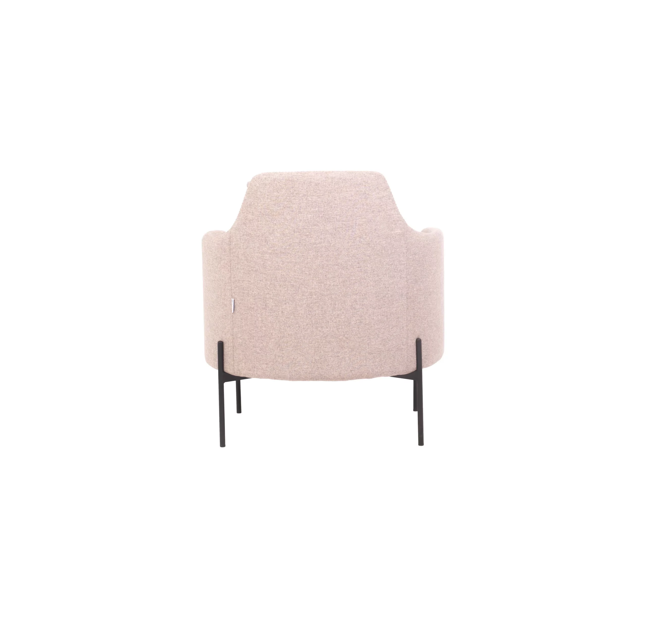 A modern, minimalist room featuring a light grey armchair on a geometric round rug, adjacent to a potted plant and black side table, with a pendant lamp above casting a warm glow.