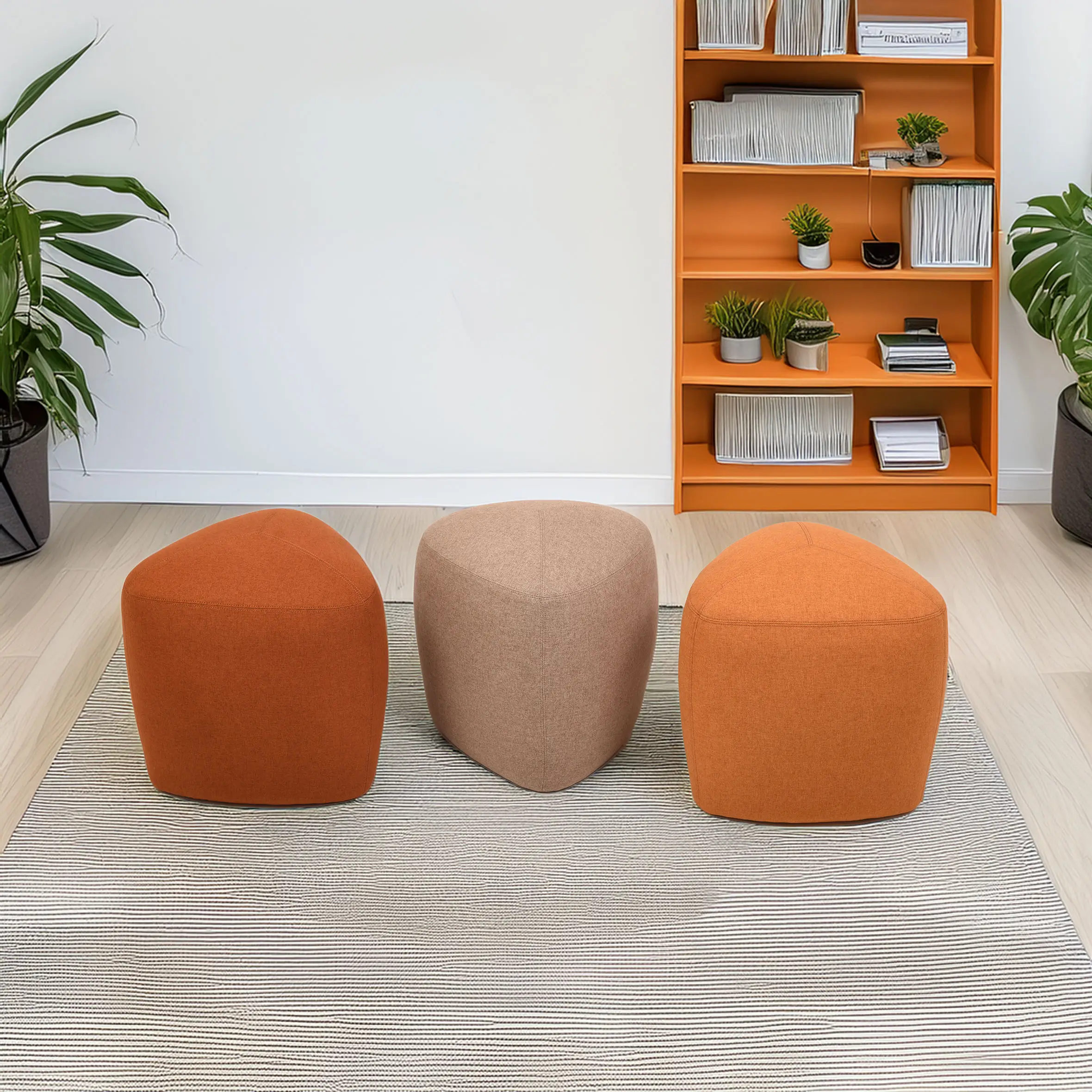 Three colorful, modern ottomans in orange and beige on a striped rug, flanked by potted plants. An orange bookshelf with books adds a cozy vibe.