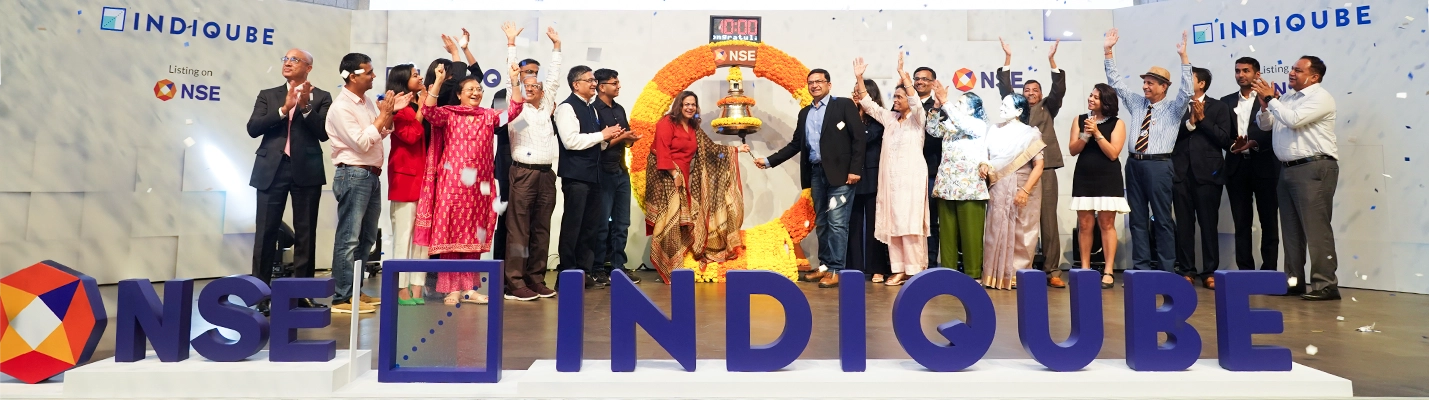 Meghna Agarwal, Co-Founder of IndiQube, speaking at NSE event with a banner reading ‘A Decade of Reimagining Workspaces’.