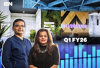 Rishi Das and Meghna Agarwal, representing the leadership team of IndiQube, stand in front of the company’s office reception area with the IndiQube logo illuminated behind them.